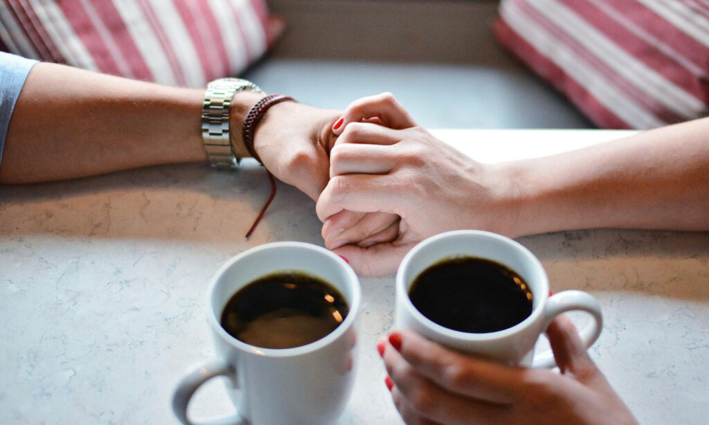 couple holding hands and connecting over coffee